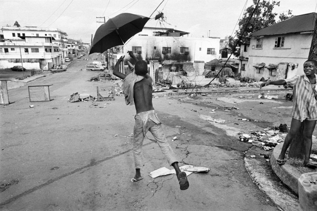 Gervasio Sánchez. Un niño juega con un paraguas en la avenida principal destruida por los combates Monrovia (Liberia), 1996