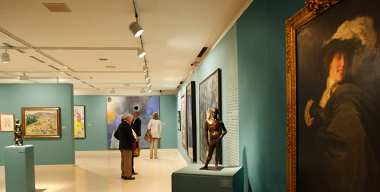 Vista de la exposición con las obras dedicadas a siglo XX al fondo y el Retrato de Ena Wertheimer de Cecilio Plá en primer término